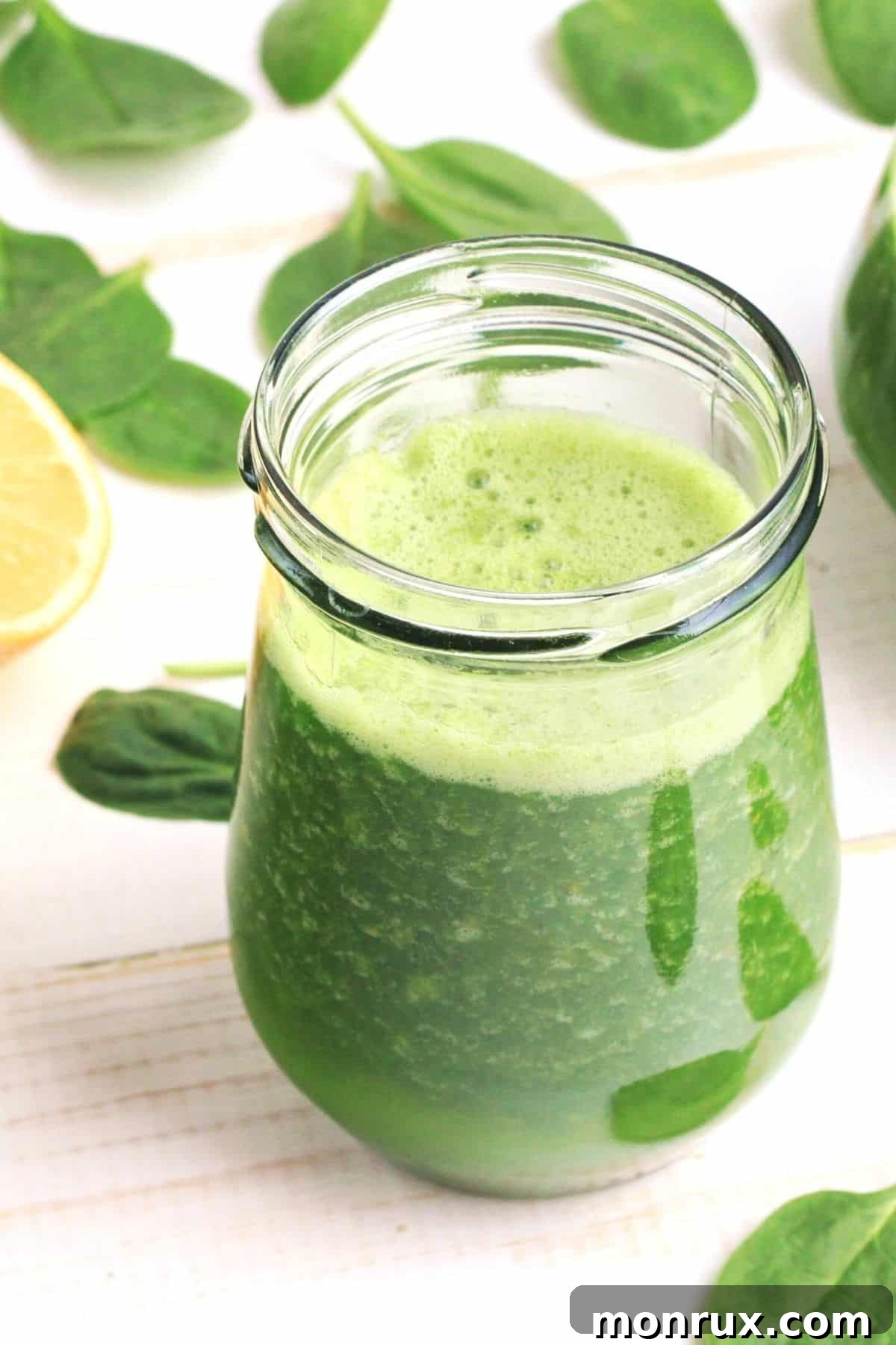 A freshly poured glass of Vitamix green juice, vibrant and ready to be enjoyed, beside the blender.