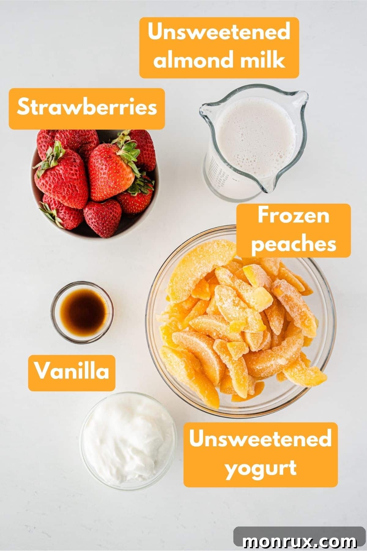 Assortment of fresh and frozen ingredients laid out for a strawberry peach smoothie, including peaches, strawberries, almond milk, and yogurt.