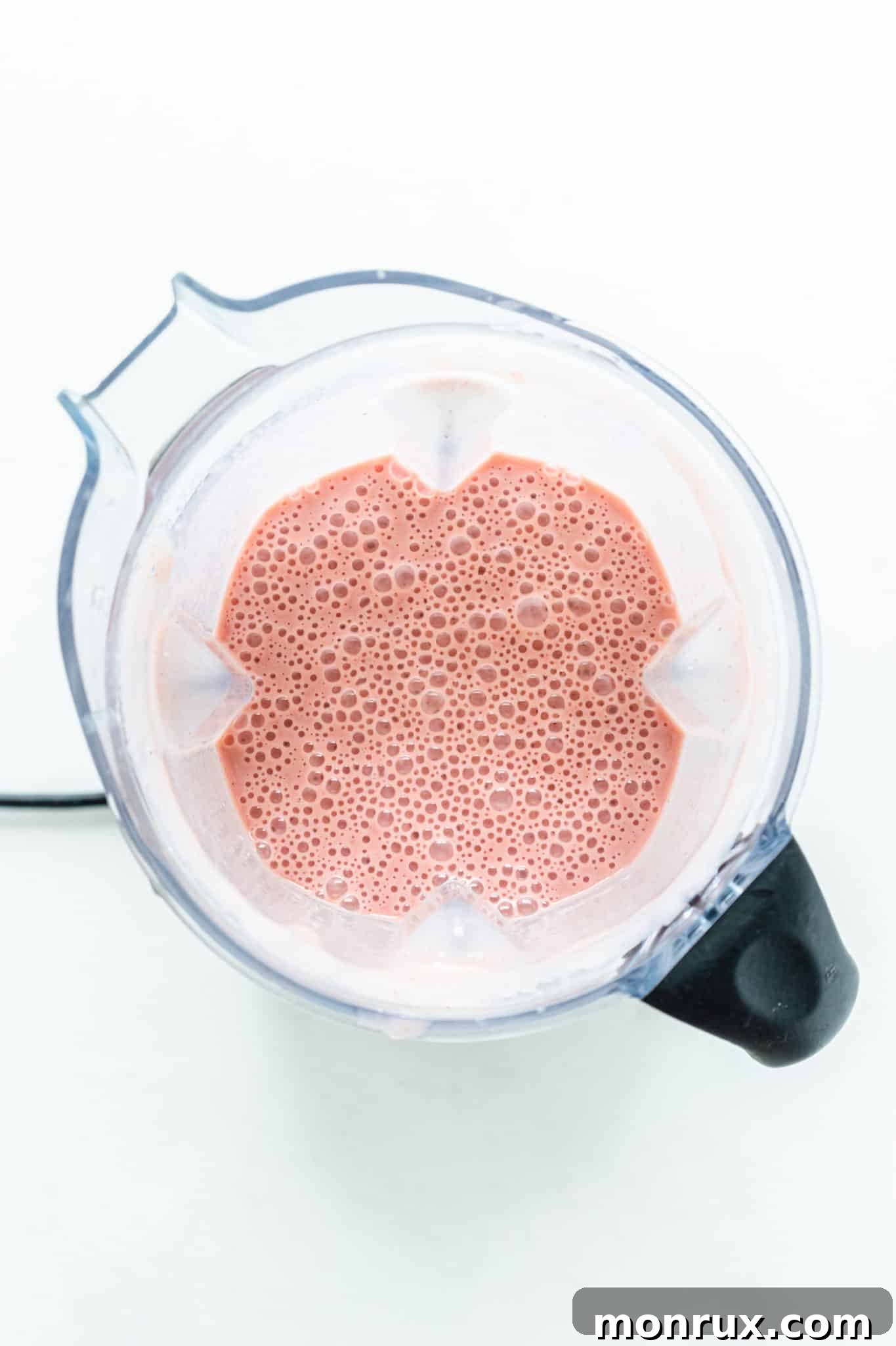 A creamy strawberry peach smoothie whirling in a blender, showing its thick texture.