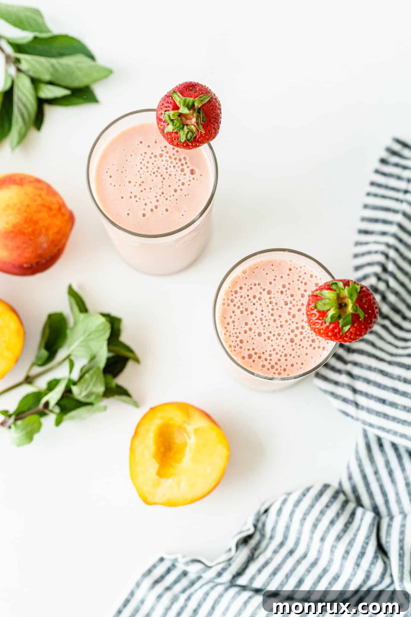 Overhead shot of two glasses of strawberry peach smoothie, beautifully presented and ready to drink.