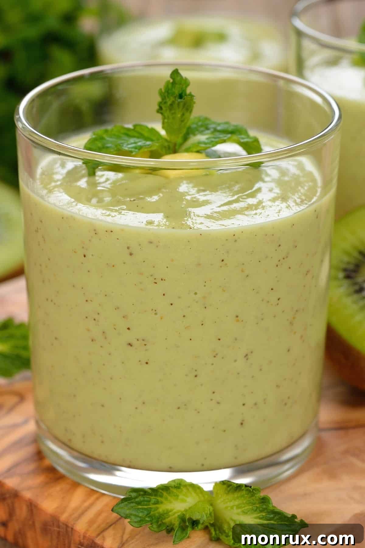 glass of green kiwi smoothie with fresh mint on top.