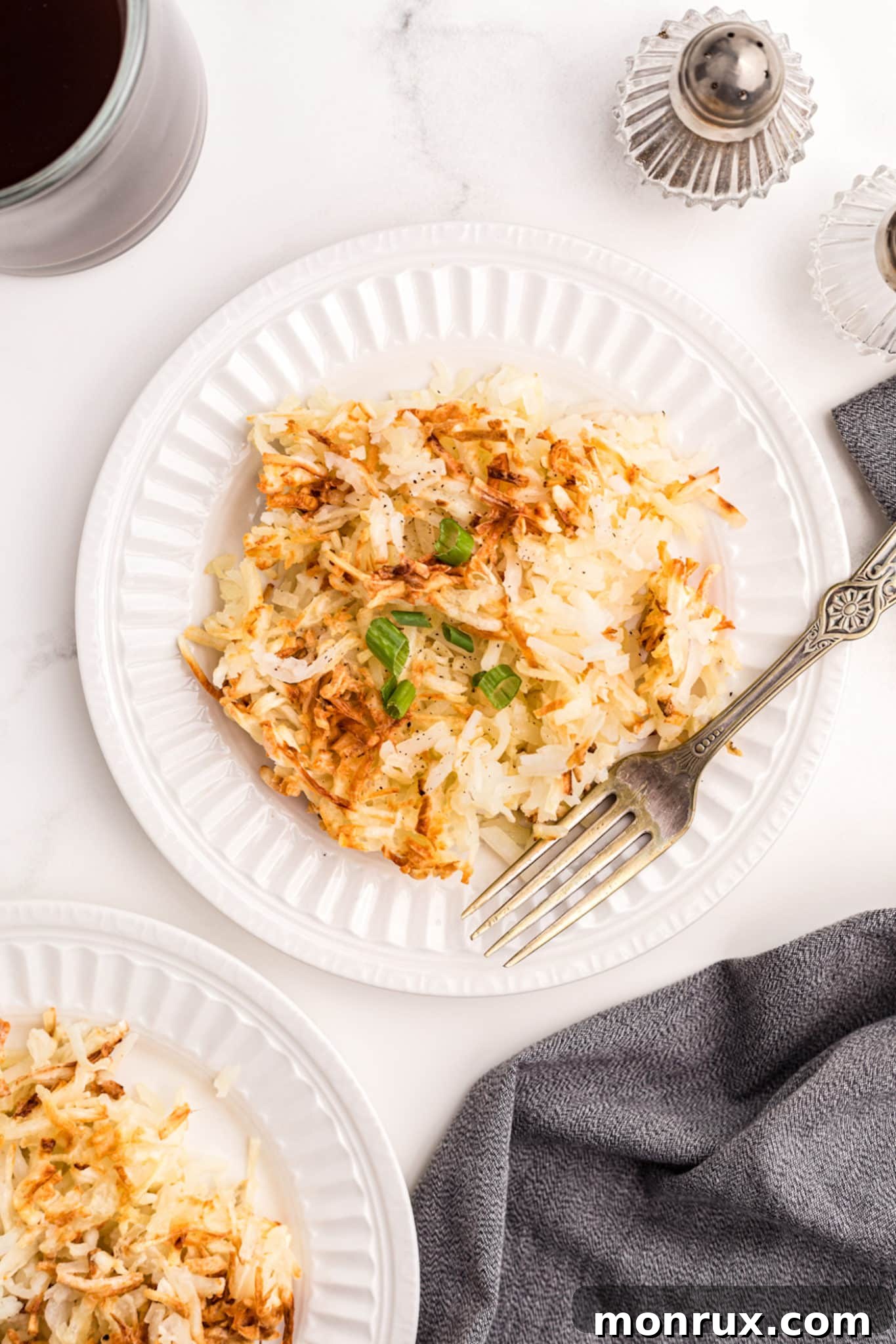 Close-up of crispy hash browns served on a white plate, garnished and ready to eat.