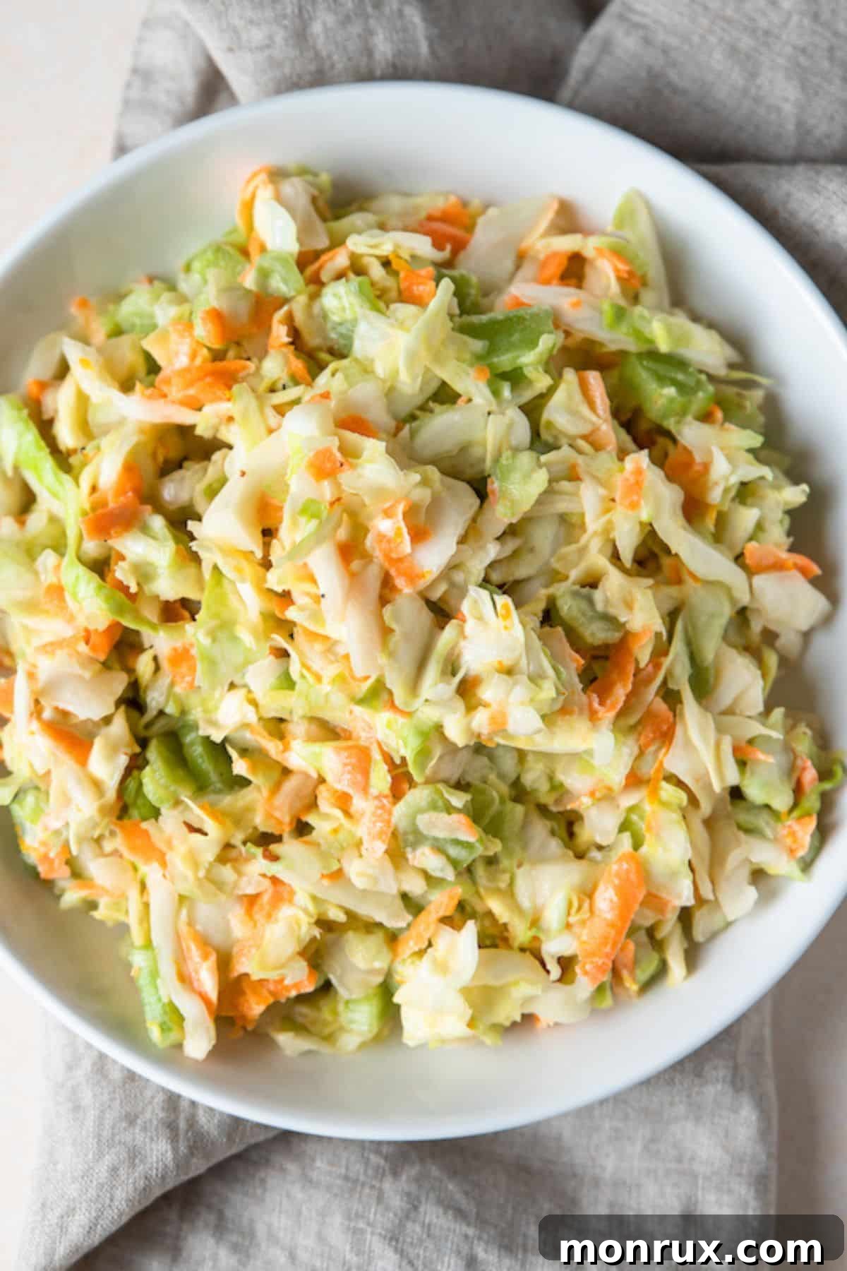 A bowl of vibrant Whole30 Coleslaw, showcasing shredded cabbage, carrots, and pineapple tidbits, dressed in a creamy, healthy sauce.