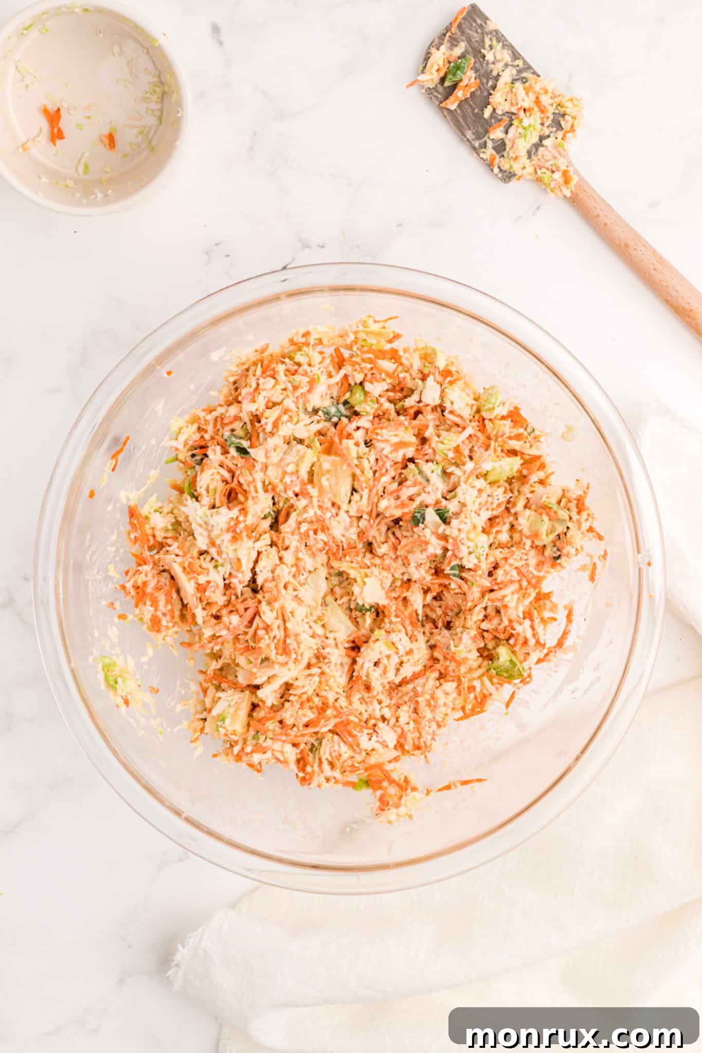 Creamy Whole30 Coleslaw, fully mixed and stirred, with carrots and cabbage coated in dressing, in a large bowl.