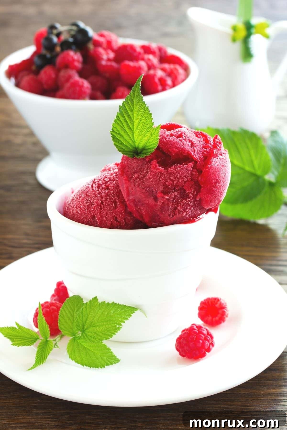 A vibrant bowl of mixed berry sorbet, garnished with a sprig of fresh mint, ready to be enjoyed.