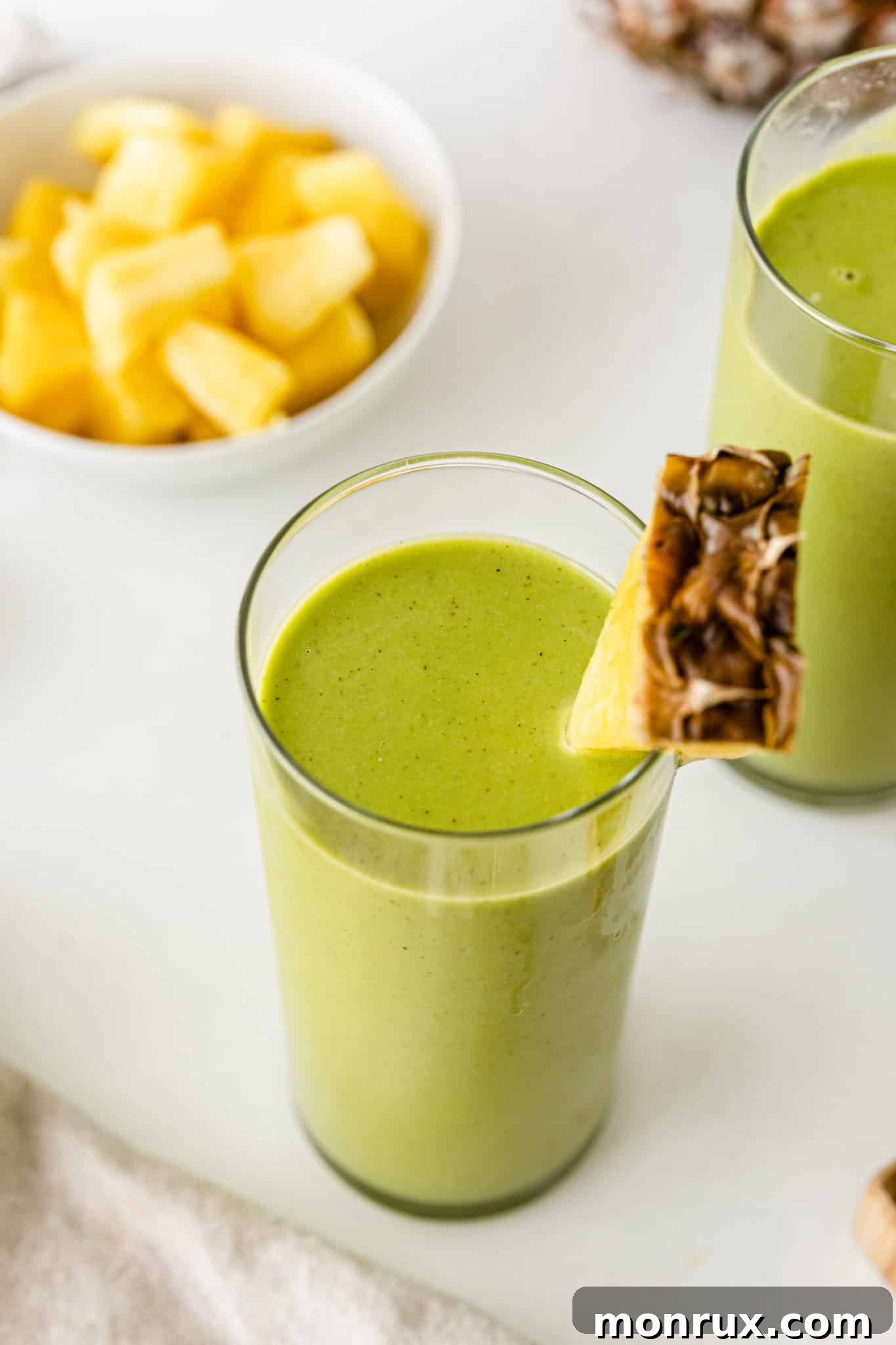 green smoothie served in a glass with a wedge of fresh pineapple