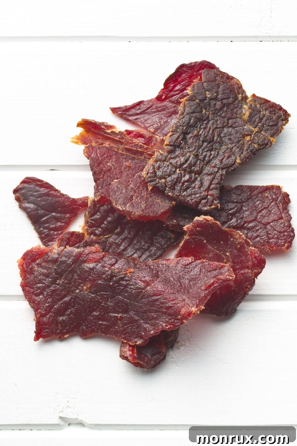 Assorted sugar-free beef jerky pieces displayed on a rustic wooden tabletop, highlighting a healthy and convenient snack option.
