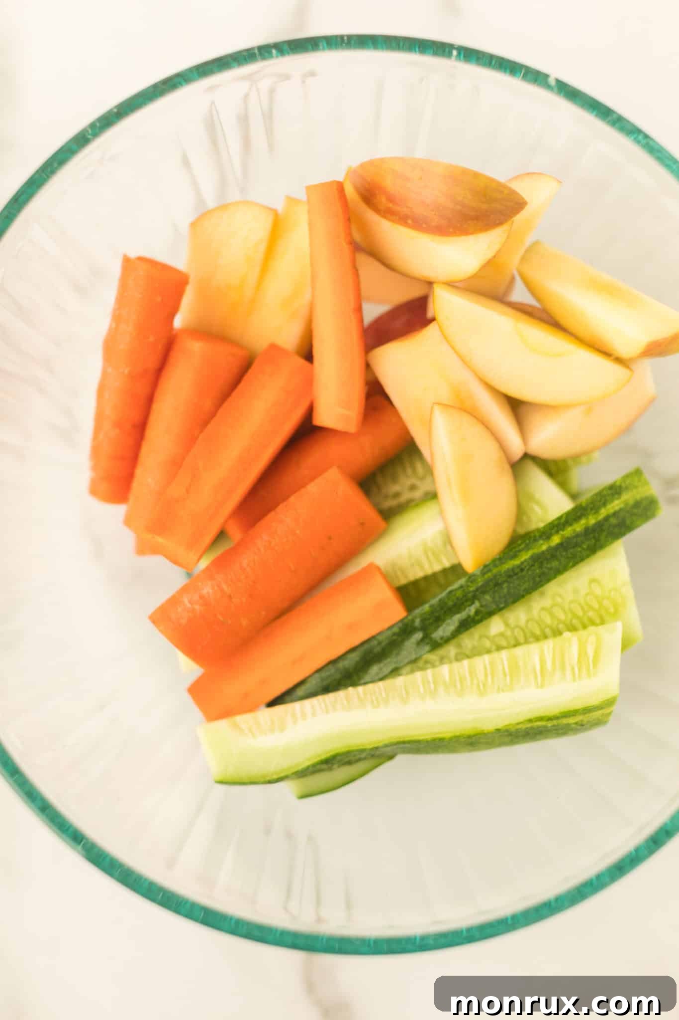 Cut up pieces of apple, carrots, and cucumber in a bowl, ready for juicing.