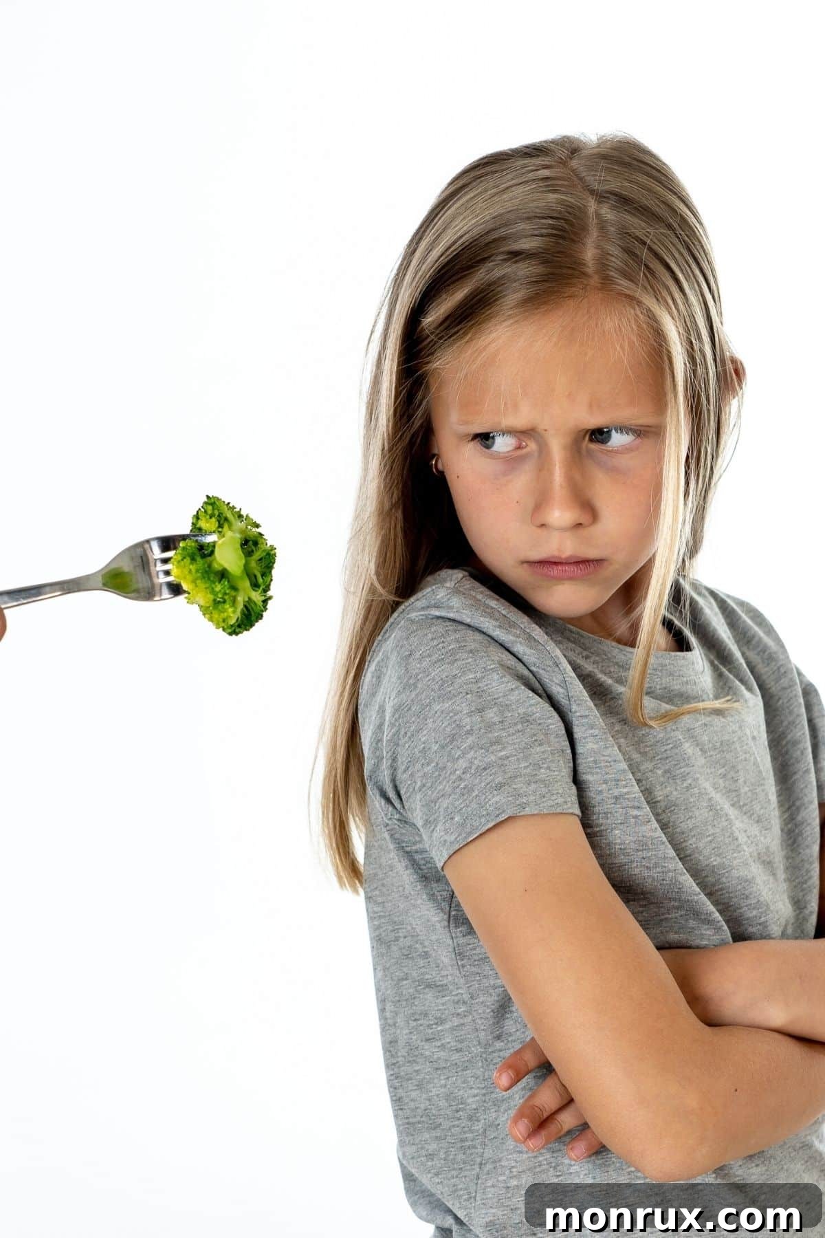 young girl refusing a bite of broccoli, representing a picky eater's challenge.