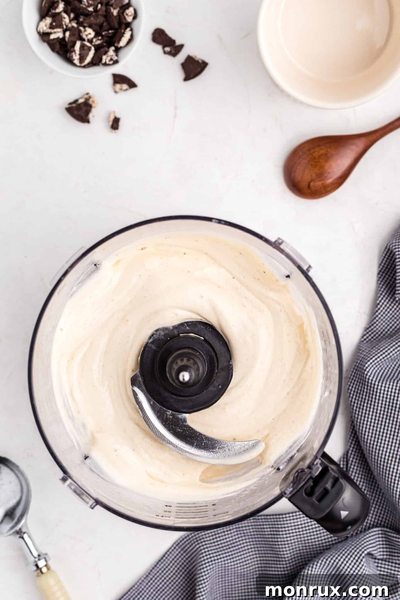 Ingredients for cookies and cream nice cream being blended in a food processor, showcasing the creamy base before churning.