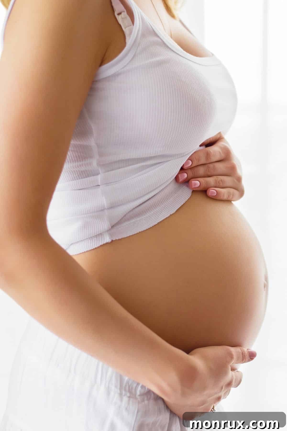 A pregnant woman gently cradling her baby bump, symbolizing the importance of proper nutrition during pregnancy.