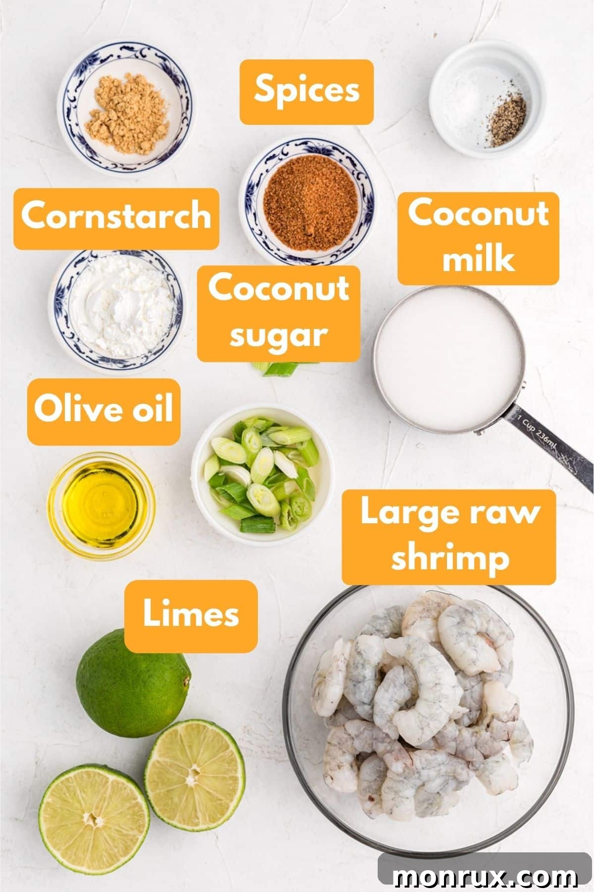 Arrangement of fresh ingredients for creamy coconut shrimp, including raw shrimp, limes, ginger, and a can of coconut milk.