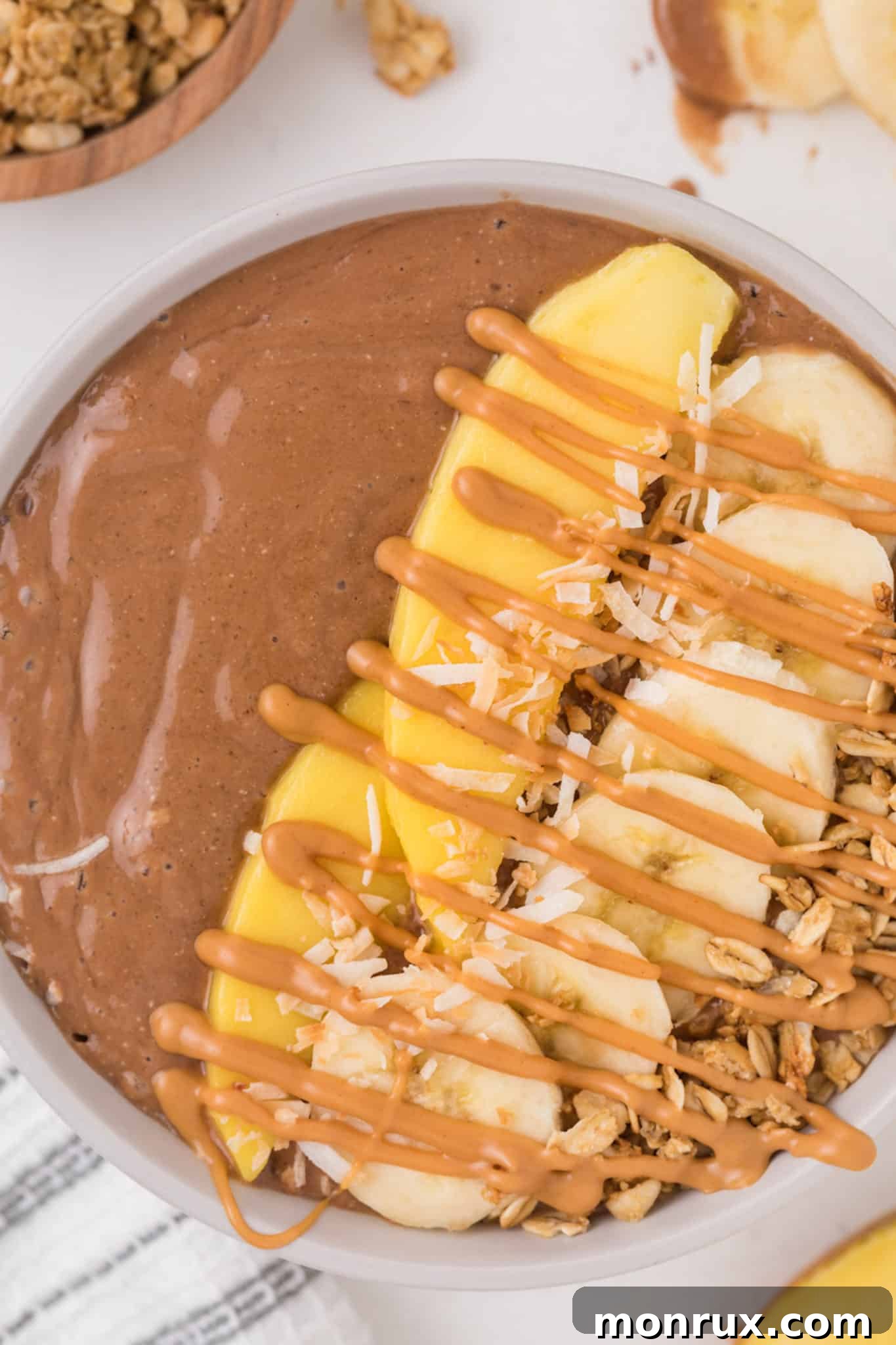 A vibrant chocolate smoothie bowl generously topped with fresh berries, sliced banana, and crunchy granola, showcasing its rich texture and appealing presentation.