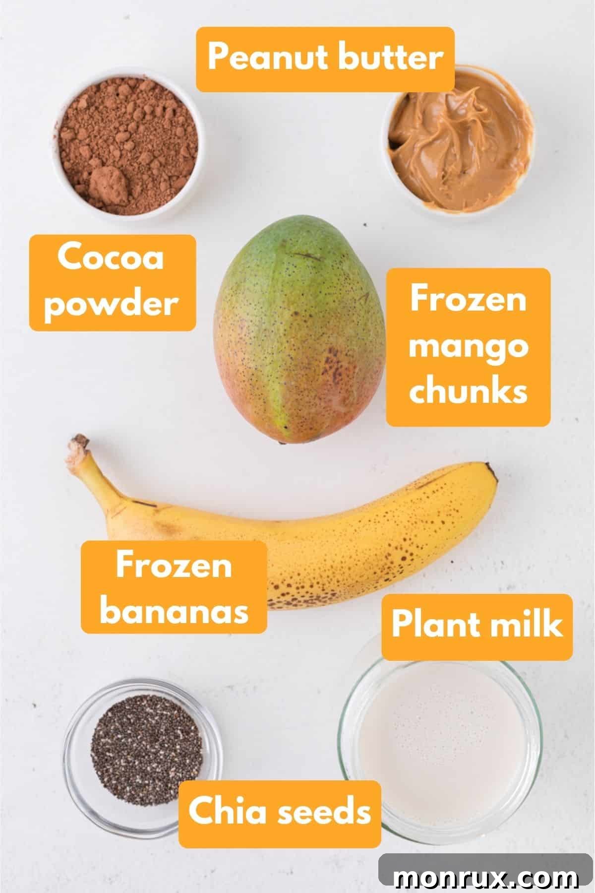 A collection of fresh and frozen ingredients laid out for a chocolate smoothie bowl, including plant milk, frozen bananas, mango, chia seeds, peanut butter, and cocoa powder.