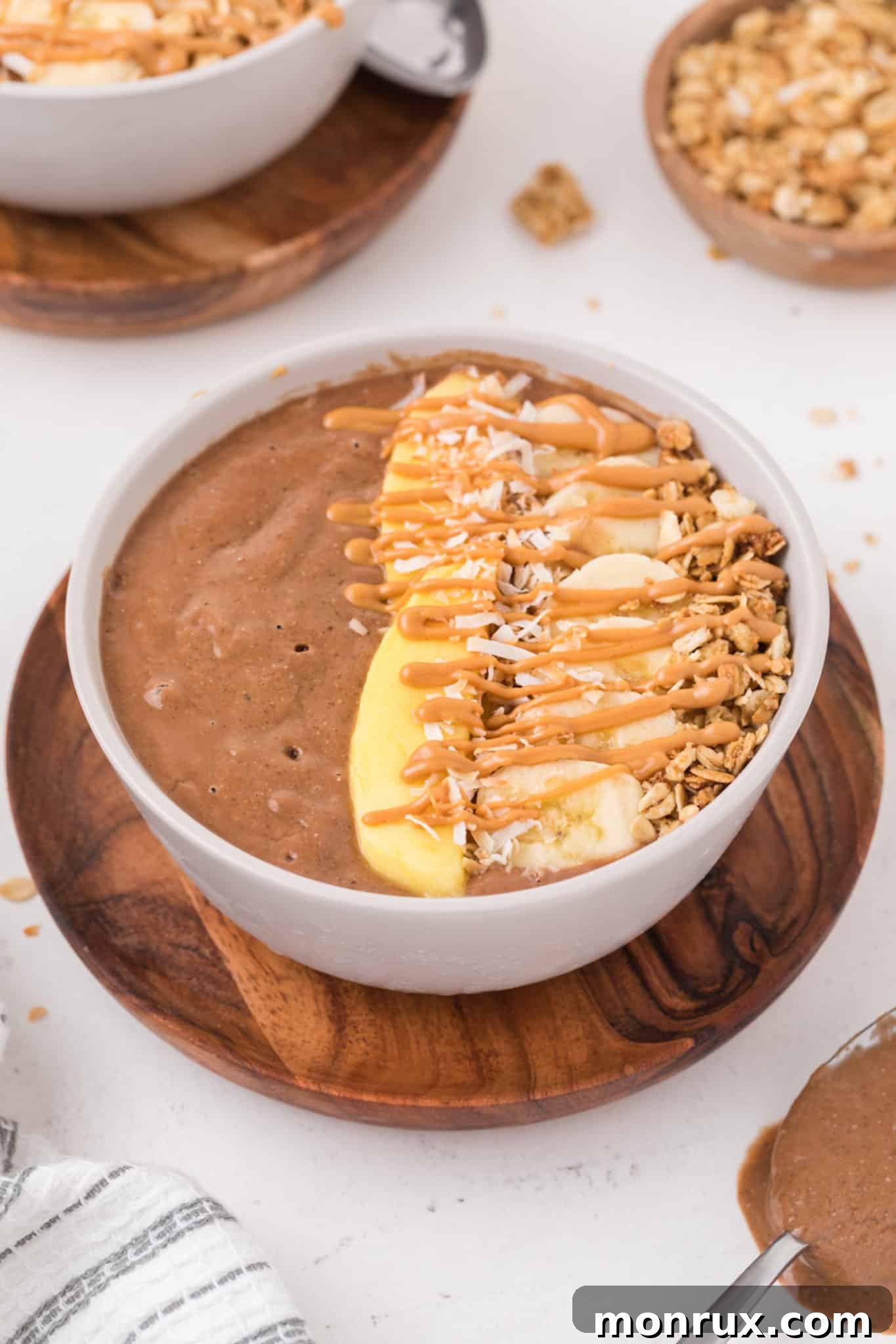 A close-up of a chocolate smoothie bowl topped with fresh fruit, including mango slices and blueberries, highlighting its appealing texture and colorful toppings.