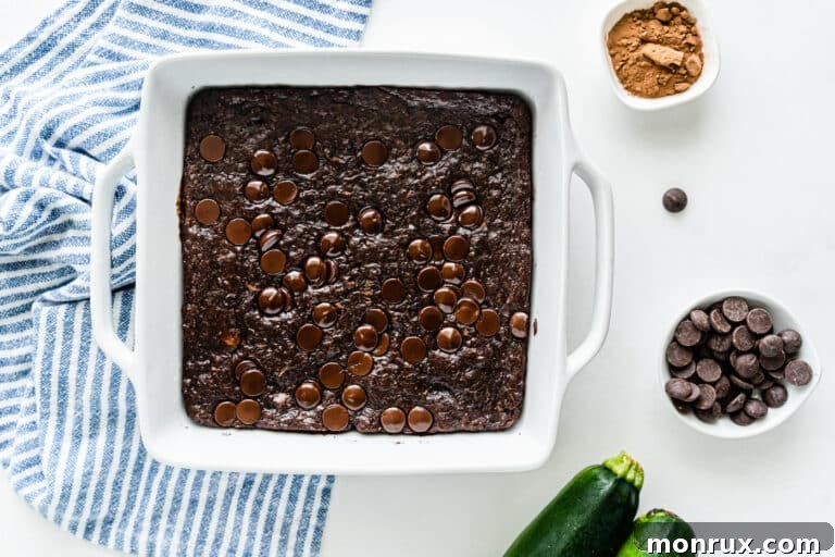 Fudgy vegan zucchini brownies baked in a square pan, glistening with chocolate goodness.