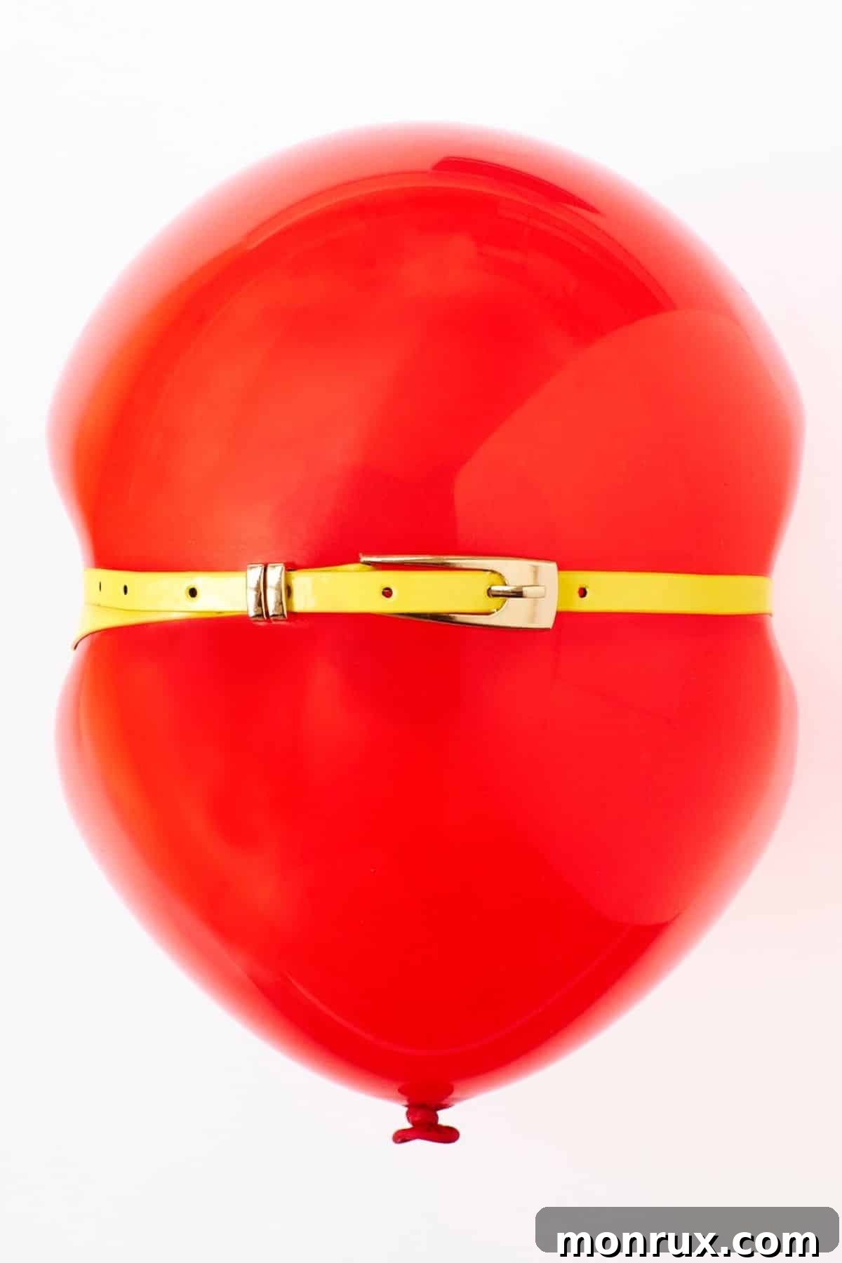 A vibrant red balloon with a yellow belt tied around its middle, symbolizing the feeling of bloating and discomfort often experienced during perimenopause.