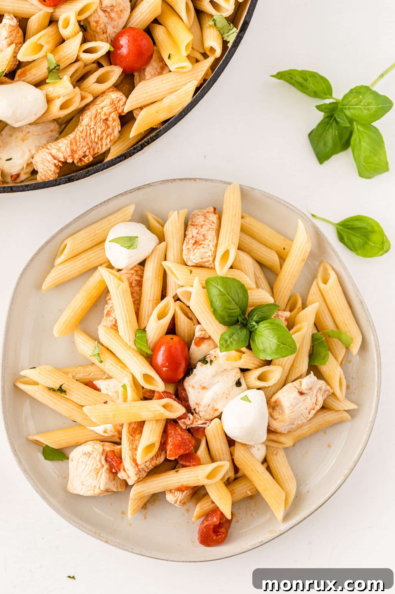 A vibrant plate of Cheesecake Factory Tomato Basil Pasta with fresh mozzarella and basil garnish.