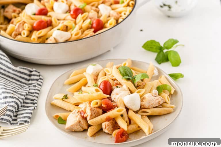 A large serving of Cheesecake Factory Tomato Basil Pasta with chicken, fresh mozzarella, and basil.