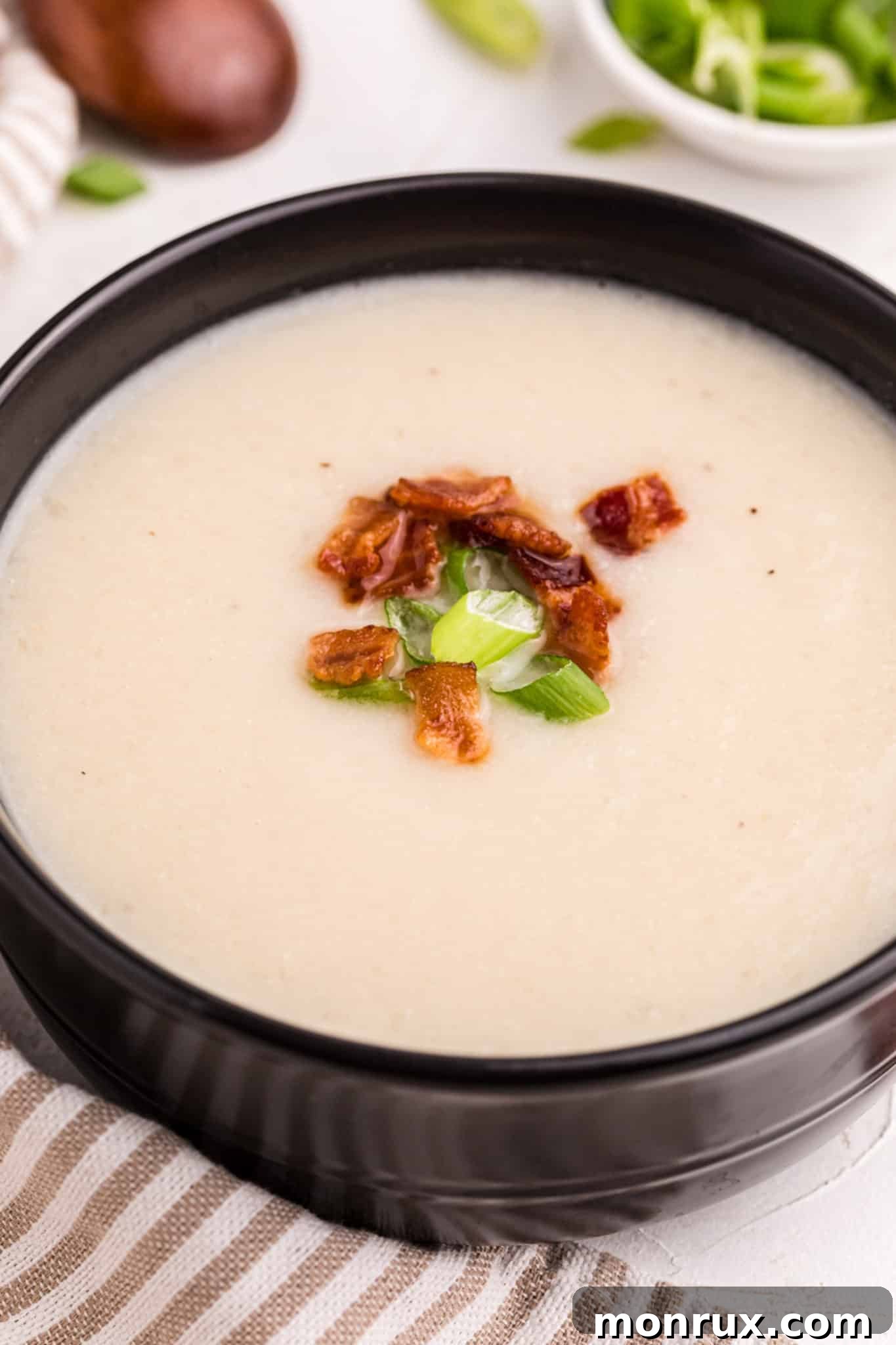 creamy cauliflower soup served in a black bowl.