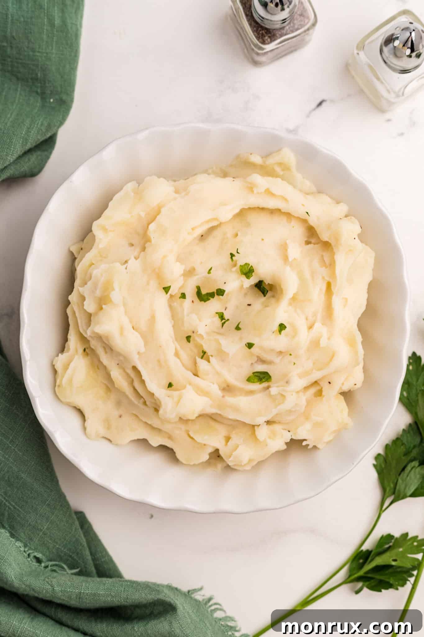 A serving bowl filled with almond milk and ghee mashed potatoes, garnished lightly.
