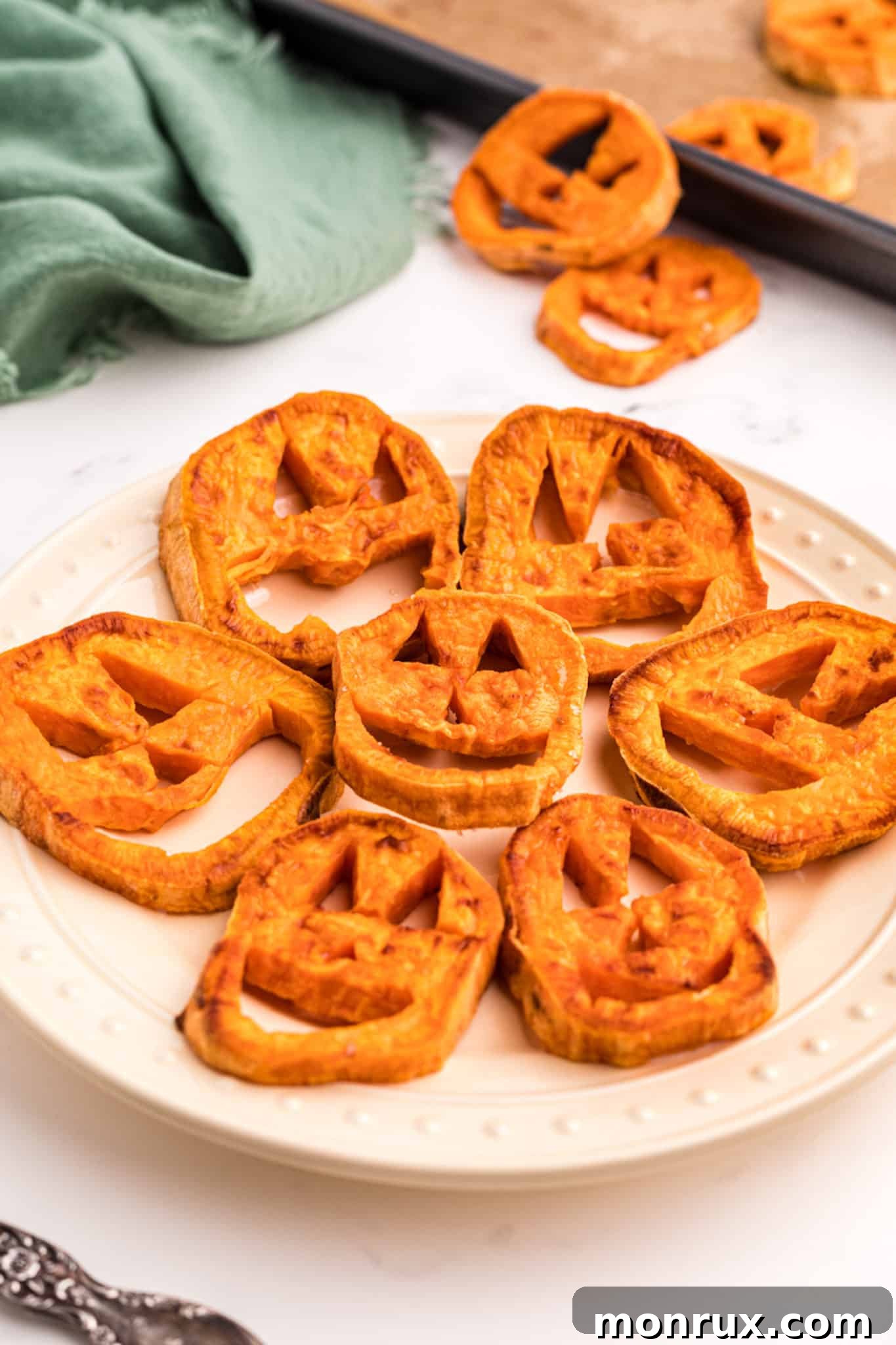 Vibrant orange sweet potato slices carved into playful Jack O'-Lantern faces, ready for a healthy Halloween celebration.