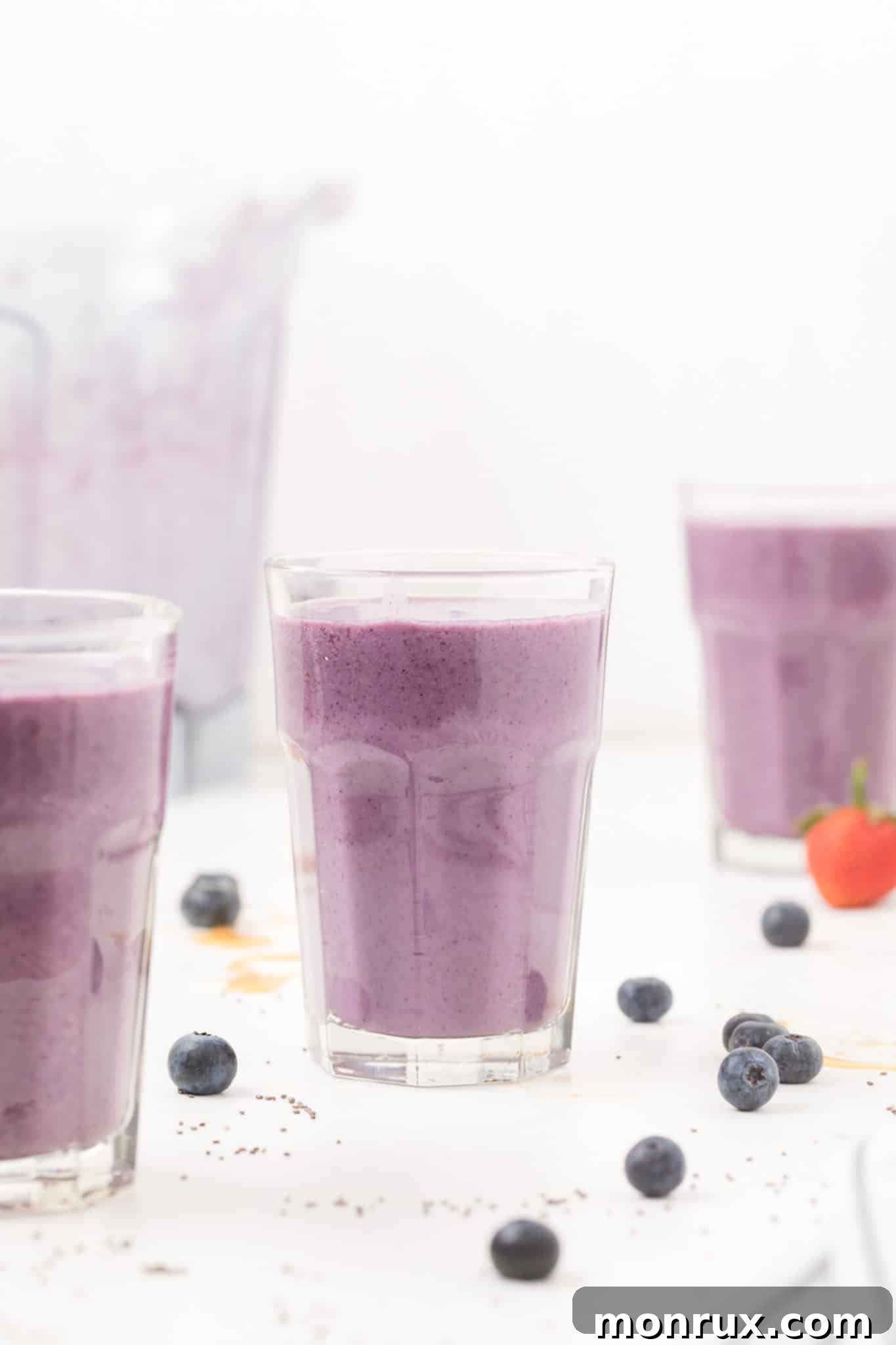 Three glasses of a vibrant purple smoothie, garnished and ready to be enjoyed.