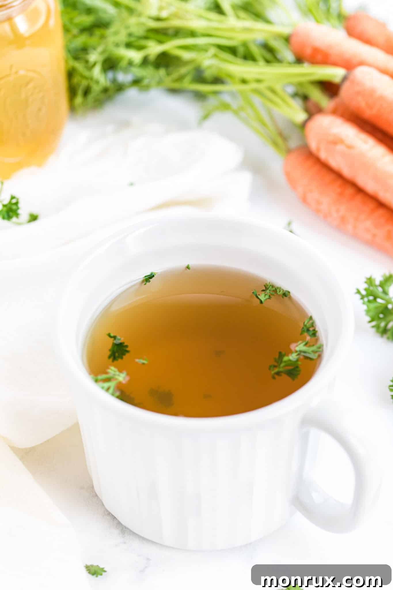 mug of instant pot veggie broth on a table with carrots.