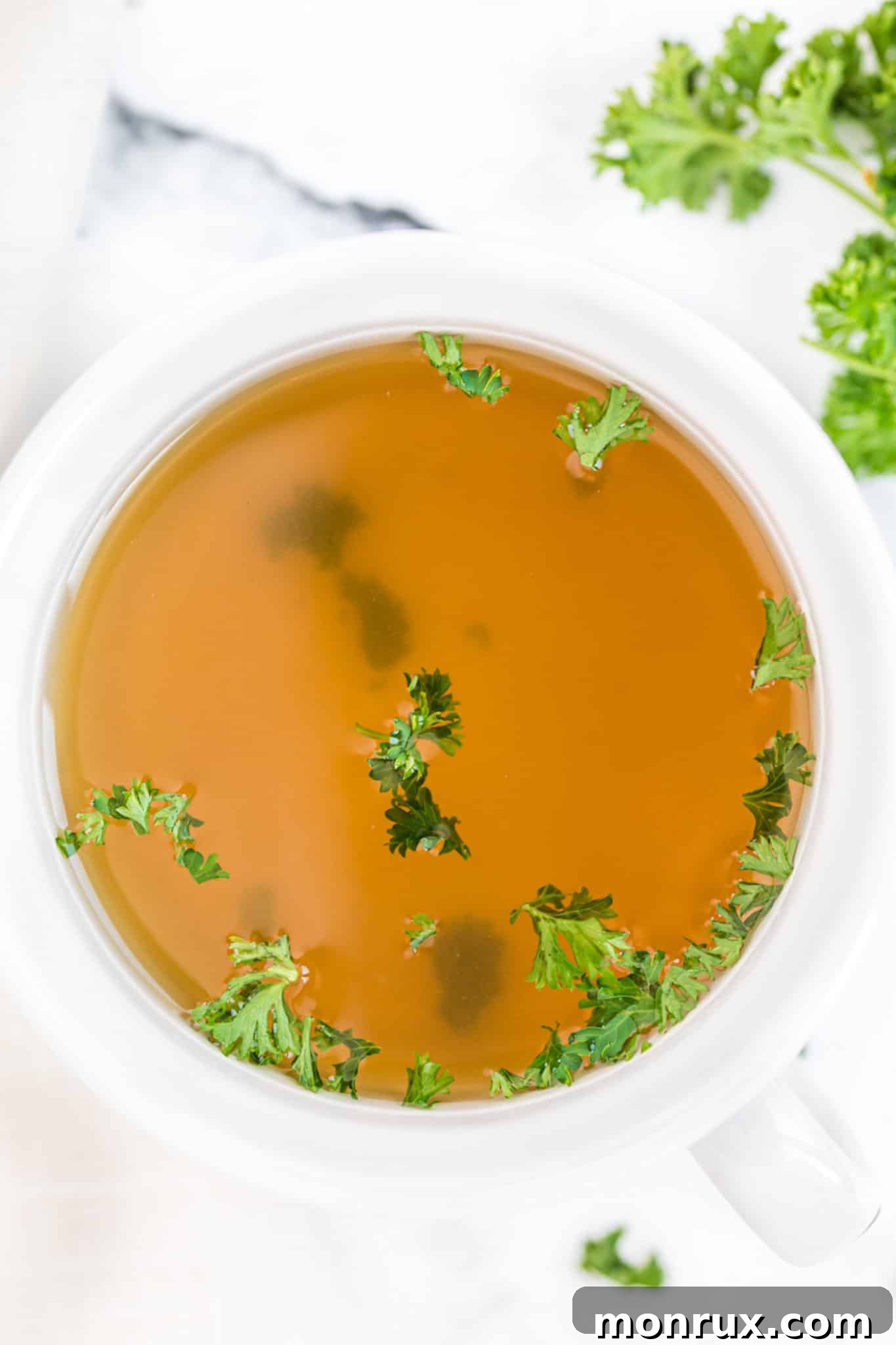 mug of instant pot vegetable broth with fresh parsley on top.