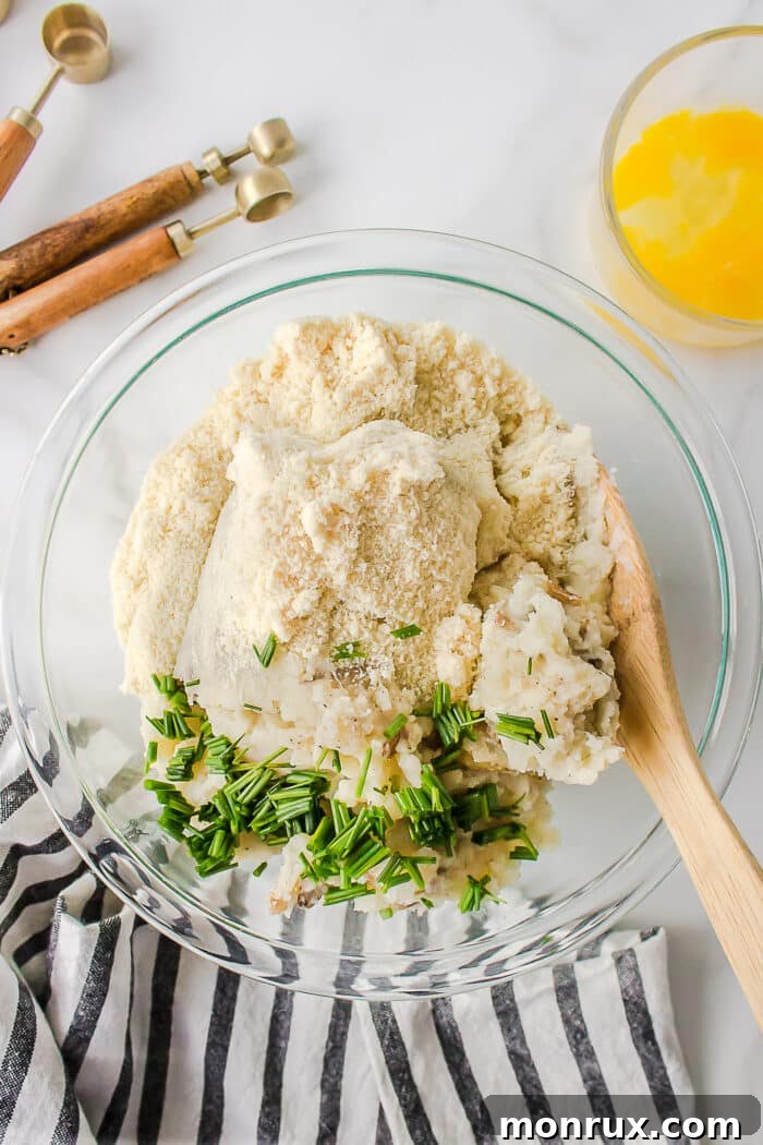 Ingredients for mashed potato fritters combined in a large mixing bowl, ready to be stirred.