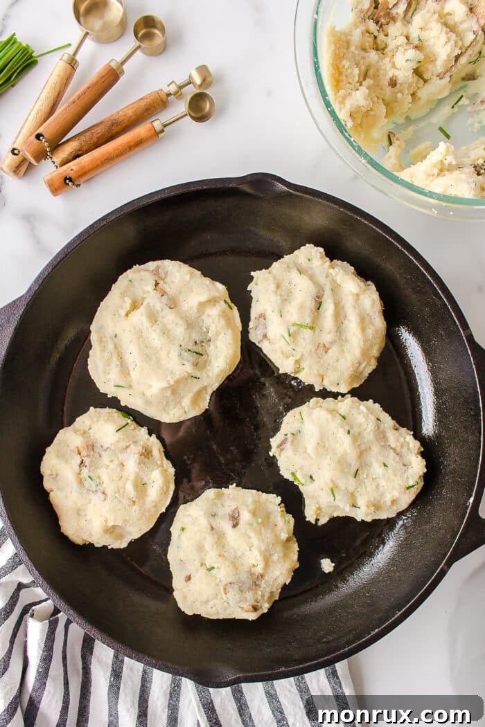 Several mashed potato fritters sizzling and turning golden brown in a hot nonstick skillet.