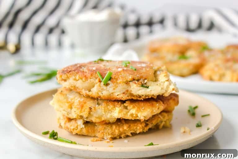 close up of crispy mashed potato fritters garnished with chives on a white plate