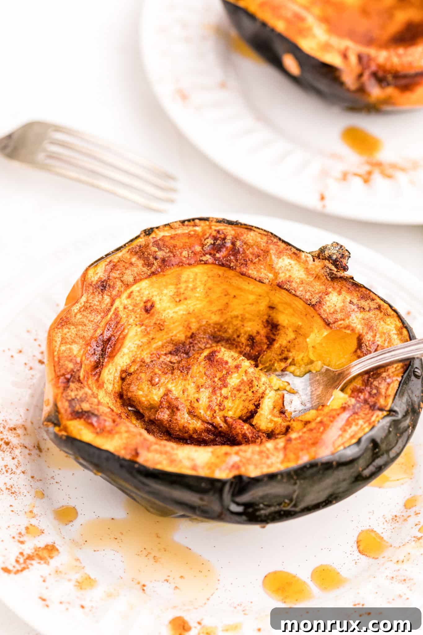 A beautifully roasted acorn squash half, mashed with cinnamon and maple syrup, served on a plate and ready to eat.