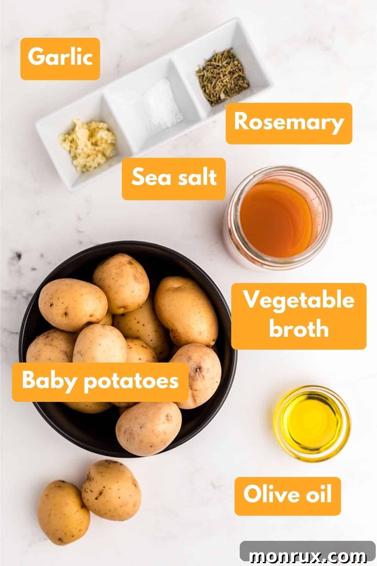 Close-up of fresh ingredients for Instant Pot baby potatoes: baby potatoes, fresh garlic cloves, dried rosemary, and a bottle of olive oil.