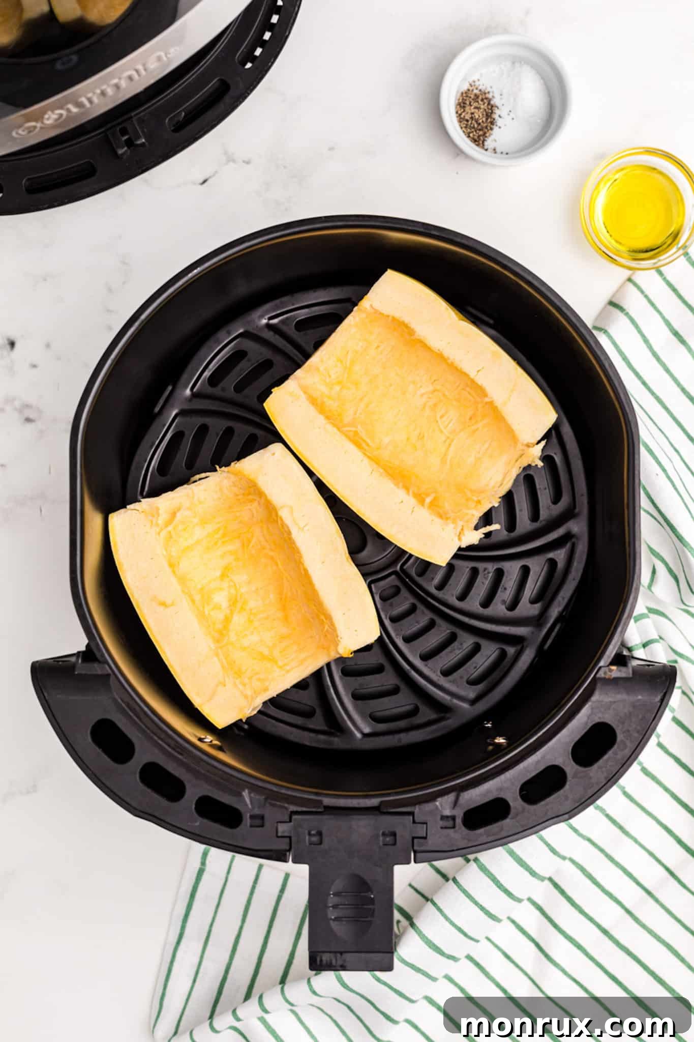 spaghetti squash halved inside air fryer basket.