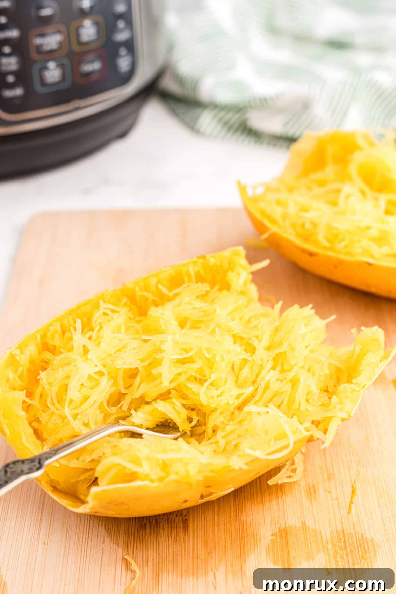 Perfectly cooked Instant Pot spaghetti squash half on a rustic cutting board, ready to be shredded into strands.