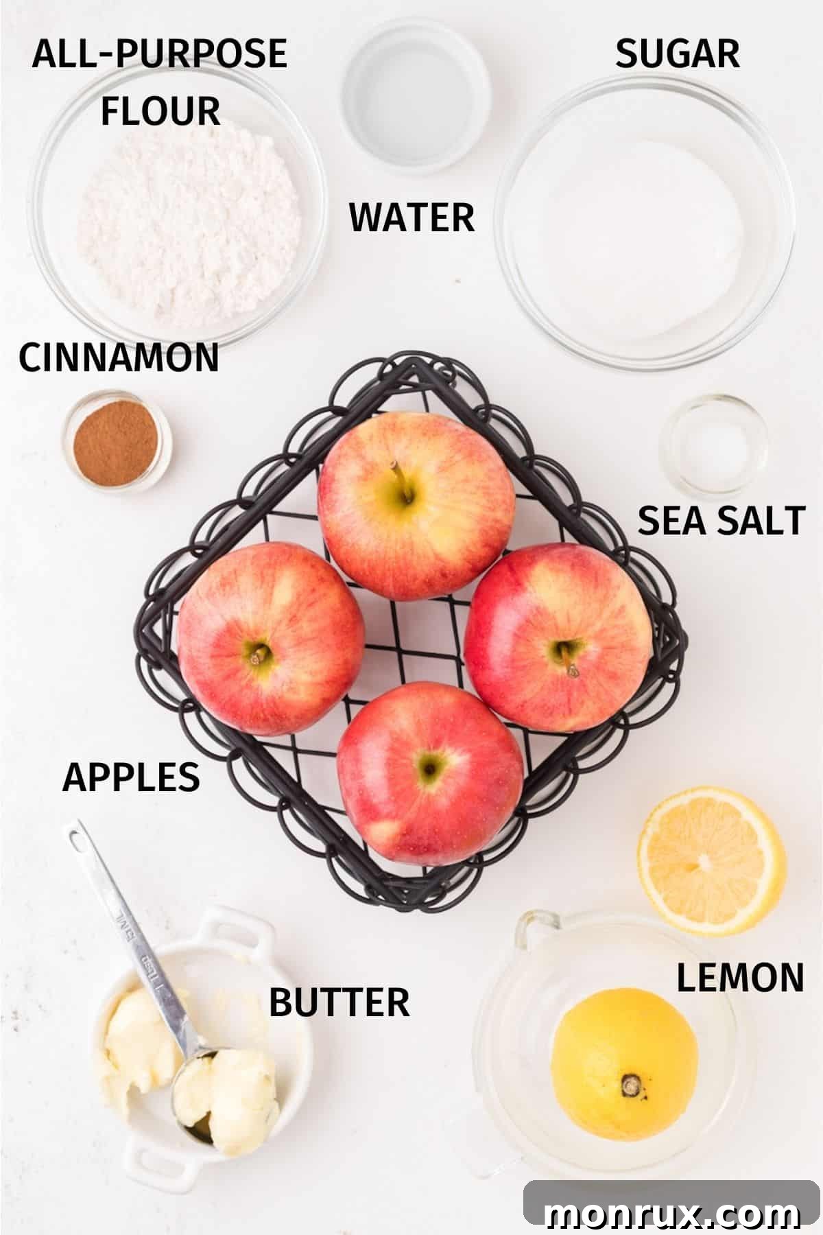 A bowl of fresh apples, flour, sugar, butter, and cinnamon, ingredients laid out for making apple crisp.