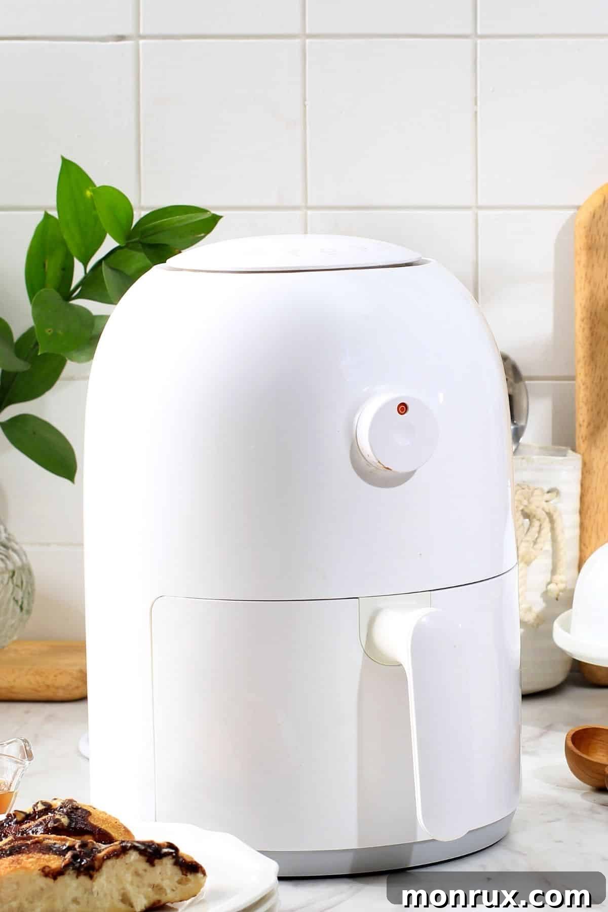 Sleek white air fryer sitting on a modern kitchen countertop, ready for use.