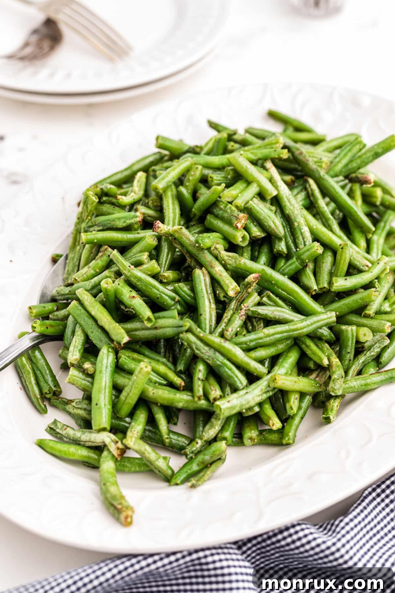A plate of perfectly cooked, crispy green beans made in an air fryer, ready to serve as a healthy side dish.