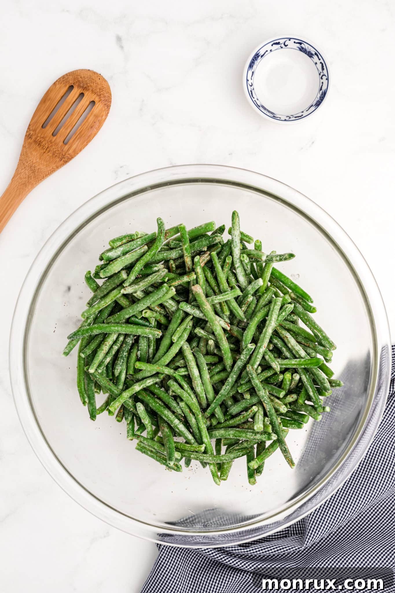 A bowl filled with frozen green beans, ready for seasoning and air frying.