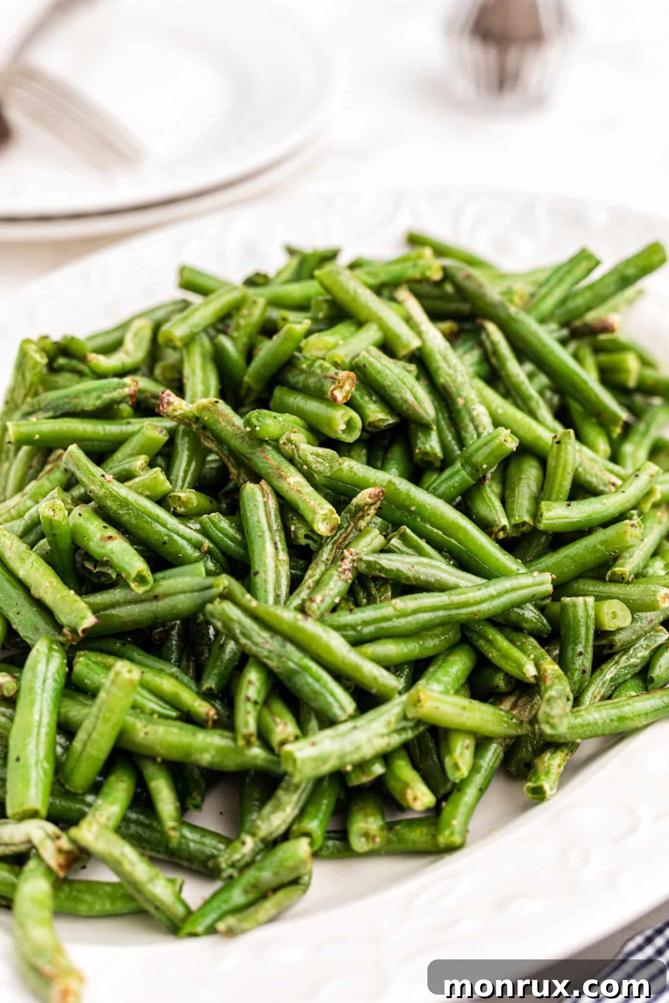 Close-up of perfectly cooked, crispy green beans inside an air fryer basket, showcasing their golden-brown texture.