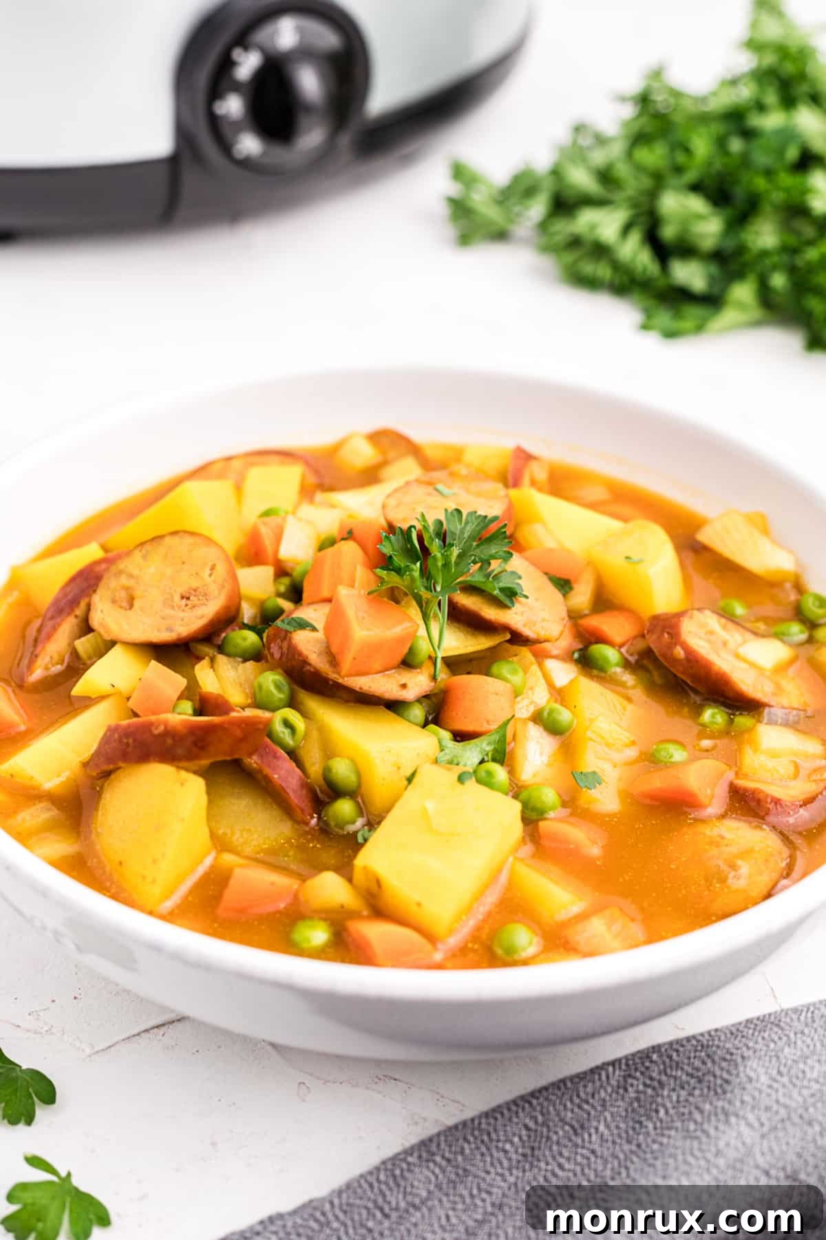 A comforting bowl of Slow Cooker Sausage Curry with tender potatoes and peas, garnished with fresh herbs.