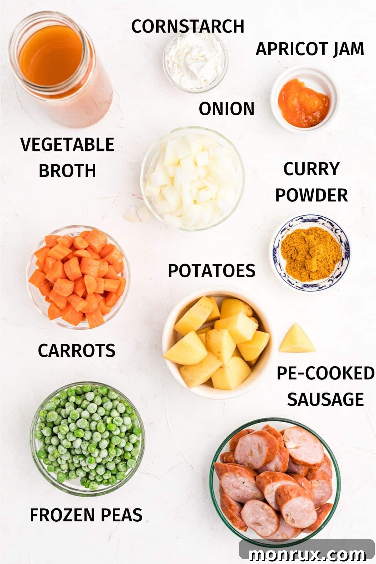 A selection of fresh ingredients including sausages, potatoes, carrots, onions, and curry powder, ready for the slow cooker.