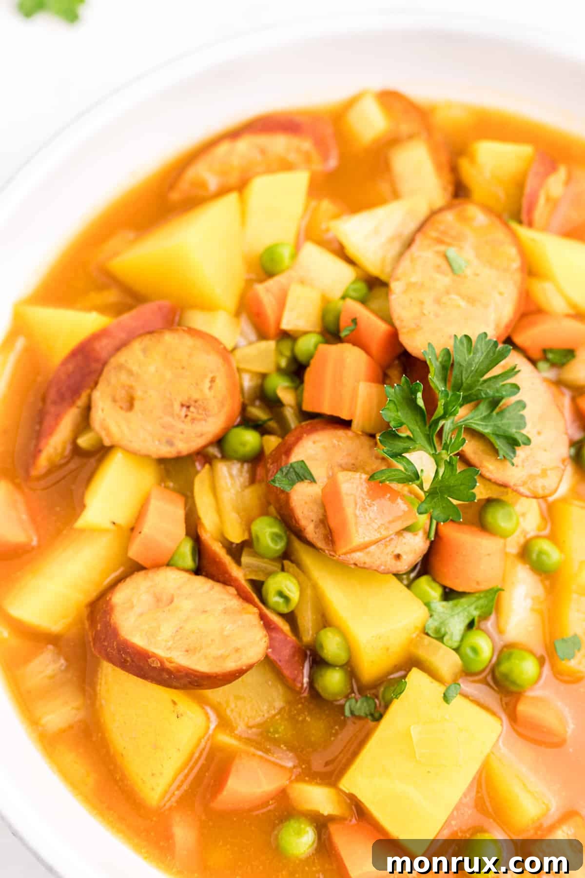 A close-up of curried sausages and tender carrots, showcasing the rich texture and vibrant colors of the dish.