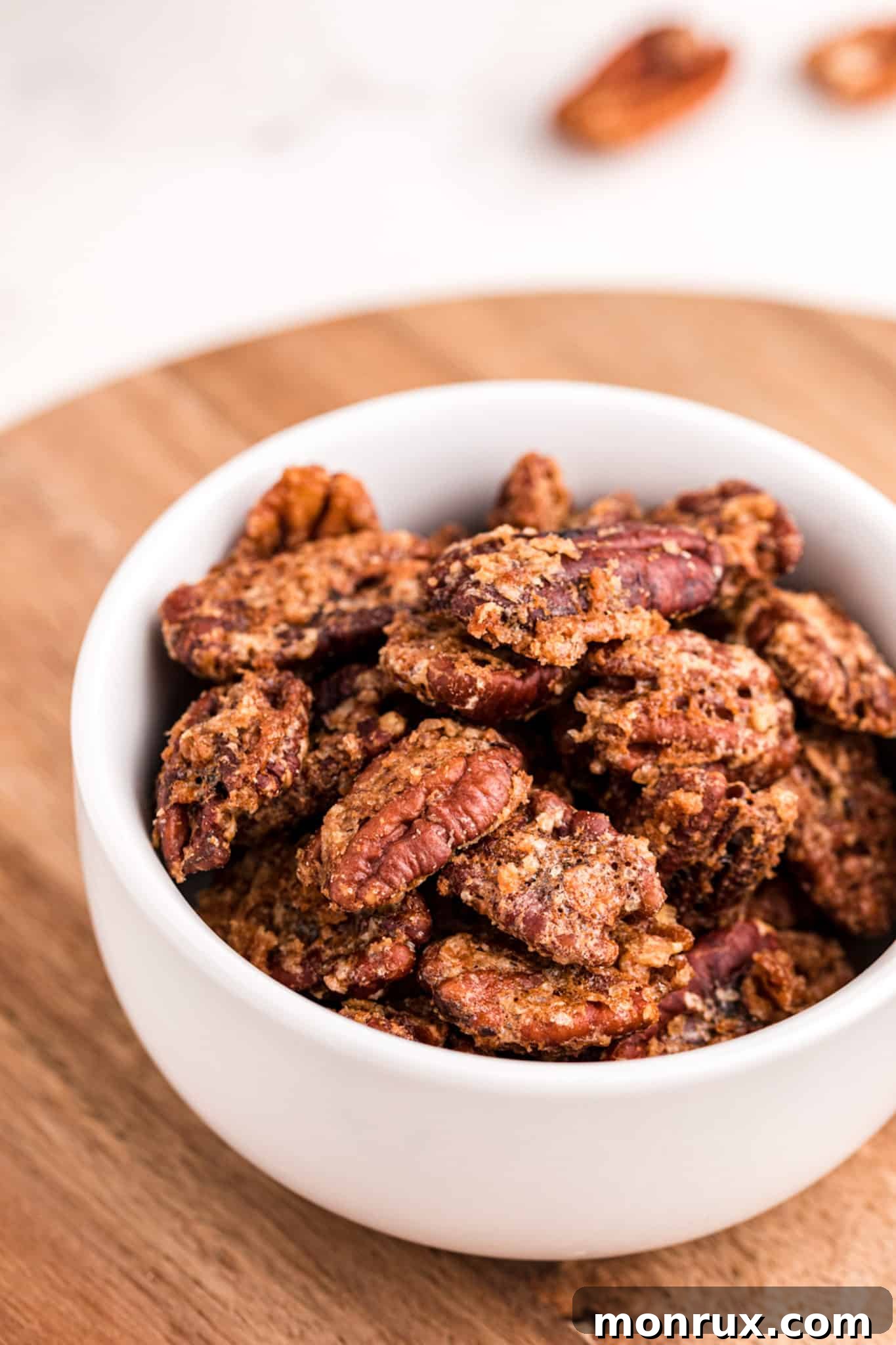 A beautifully arranged bowl of golden-brown air fryer candied pecans on a rustic wooden table, ready to be enjoyed.