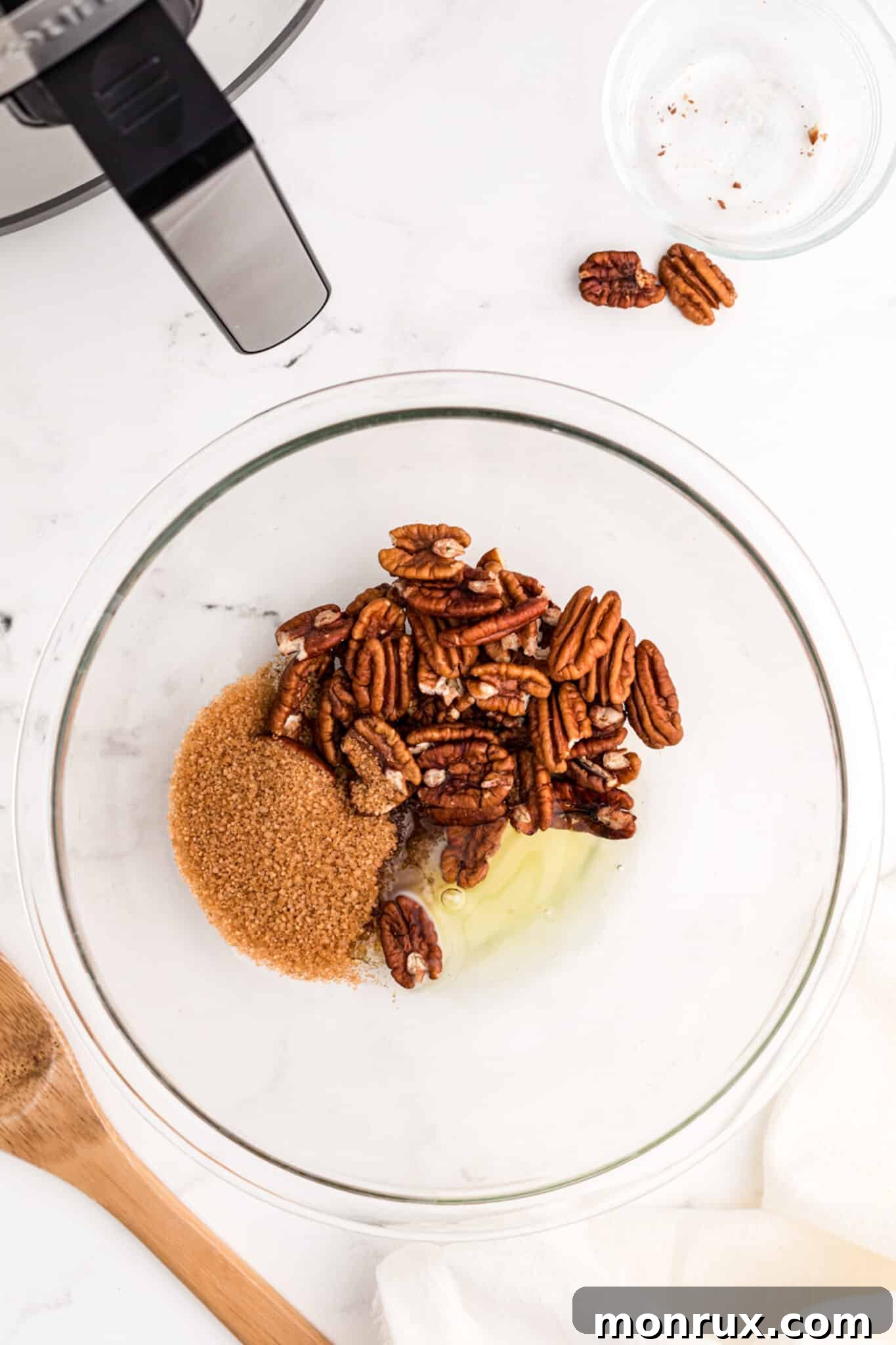 Ingredients for air fried candied pecans, including raw nuts, egg white, sugar, and melted coconut oil, displayed separately.