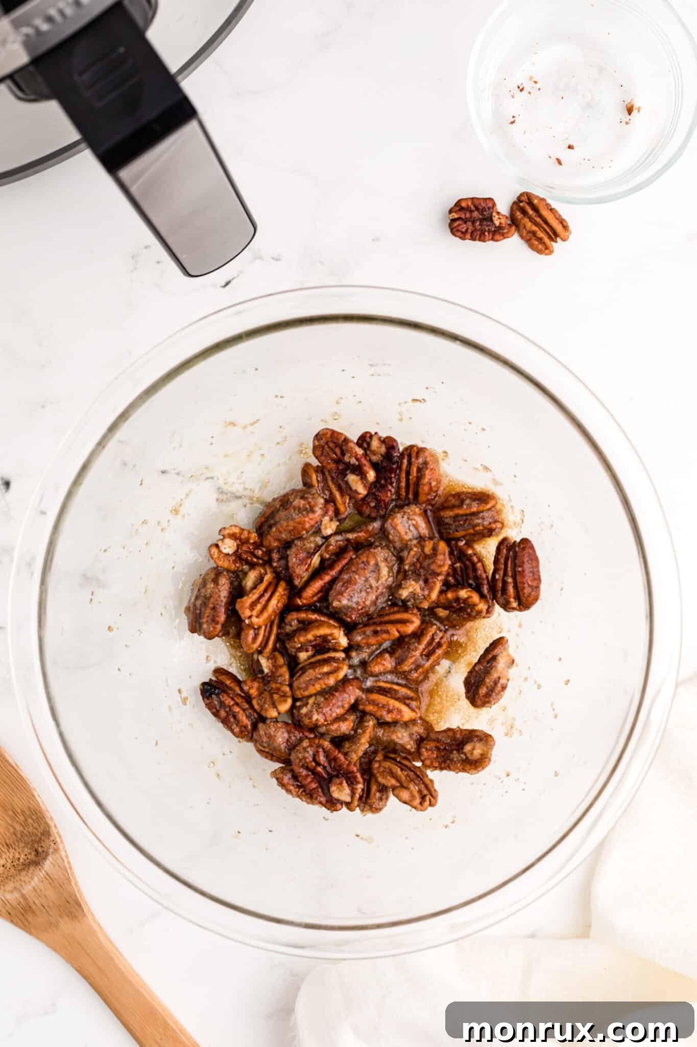 All ingredients for air fried candied pecans thoroughly mixed in a bowl, showing the pecans coated with the sweet egg white mixture.