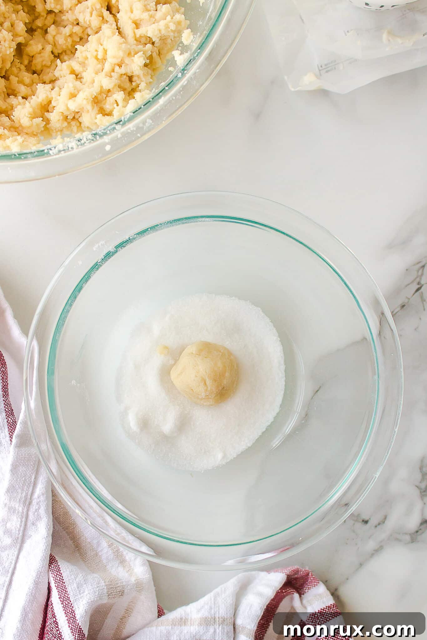 Hands rolling sugar cookie dough into small, uniform balls.