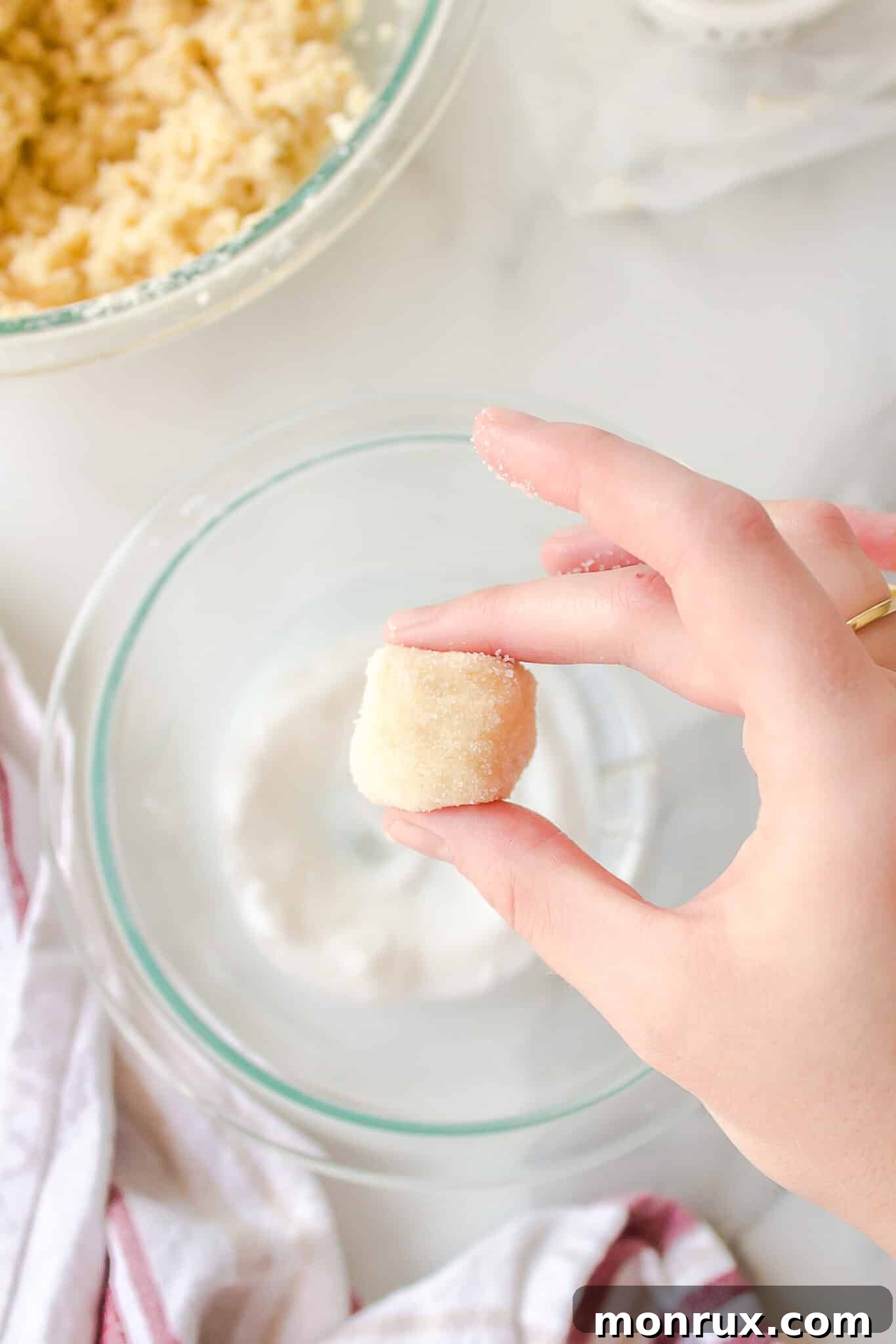 Dairy-free sugar cookie dough balls, rolled in sugar and flattened, ready for baking on a parchment-lined sheet.