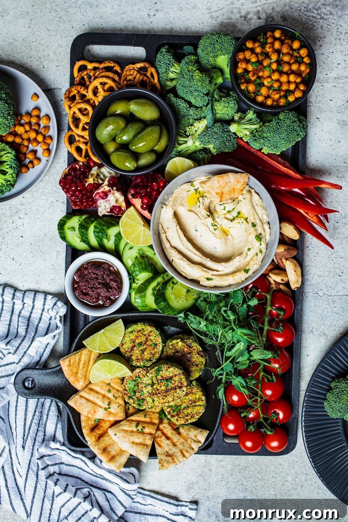 An overhead view of a vibrant vegan charcuterie board, abundant with a variety of colorful vegetables, fresh fruits, and savory dips, artfully arranged for easy grazing.